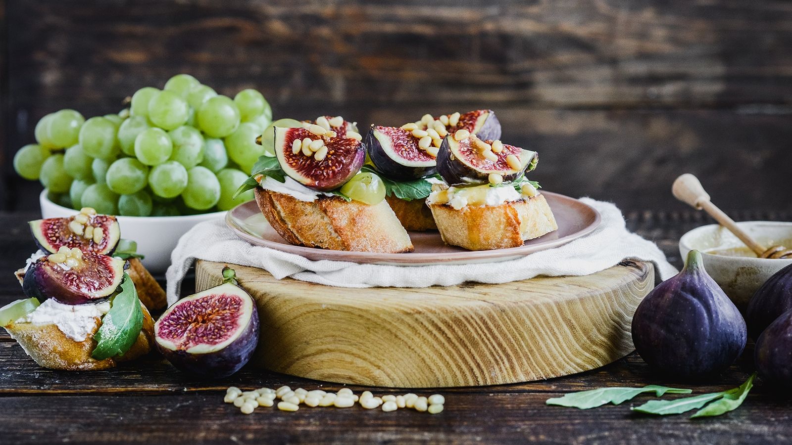 Crostini z kozim serem, winogronami i figami, posypane orzeszkami pinii